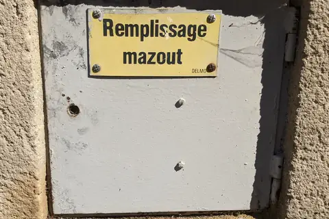 Plaque émaillée « Remplissage mazout » vissée sur le mur d'une maison, au-dessus de la trappe